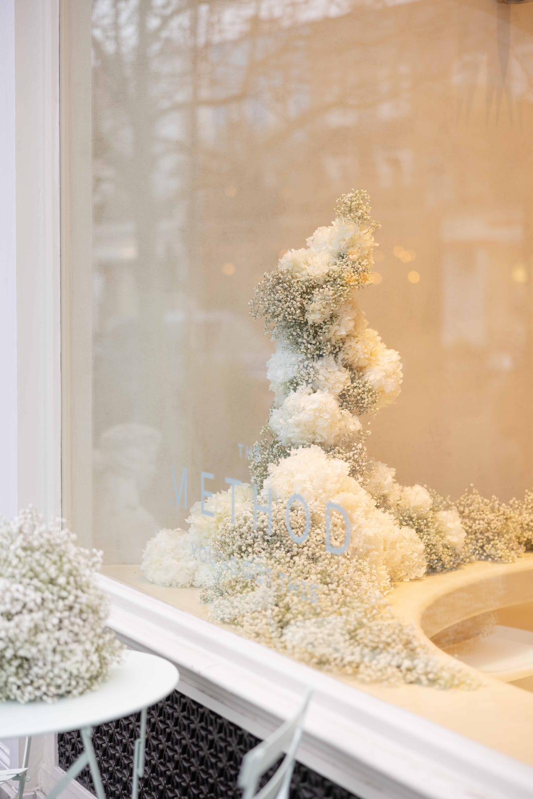 Decorative arrangement of white and light-colored flowers on a white surface with a blurred background.