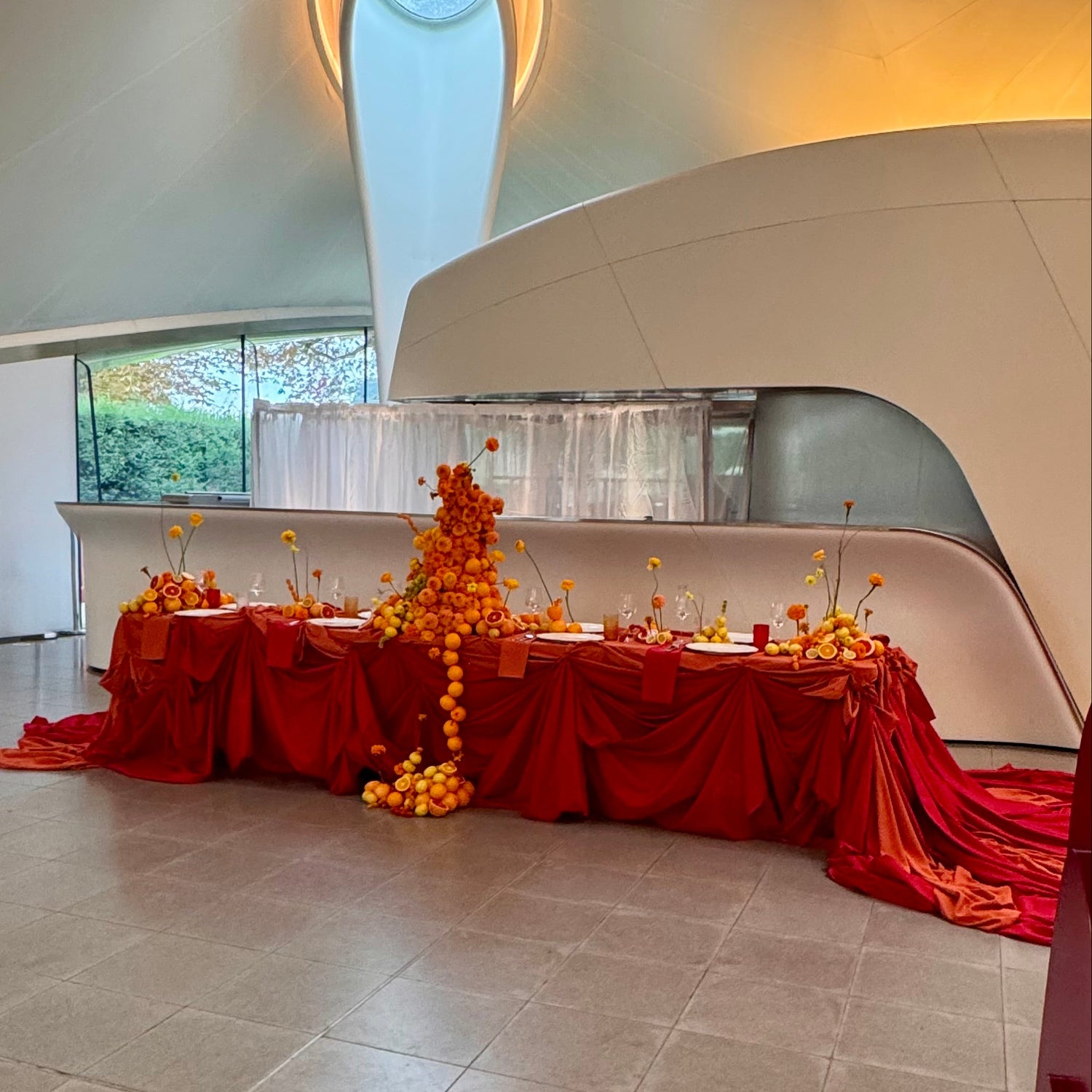 Decorative table with red tablecloth and floral arrangement in a modern architectural setting