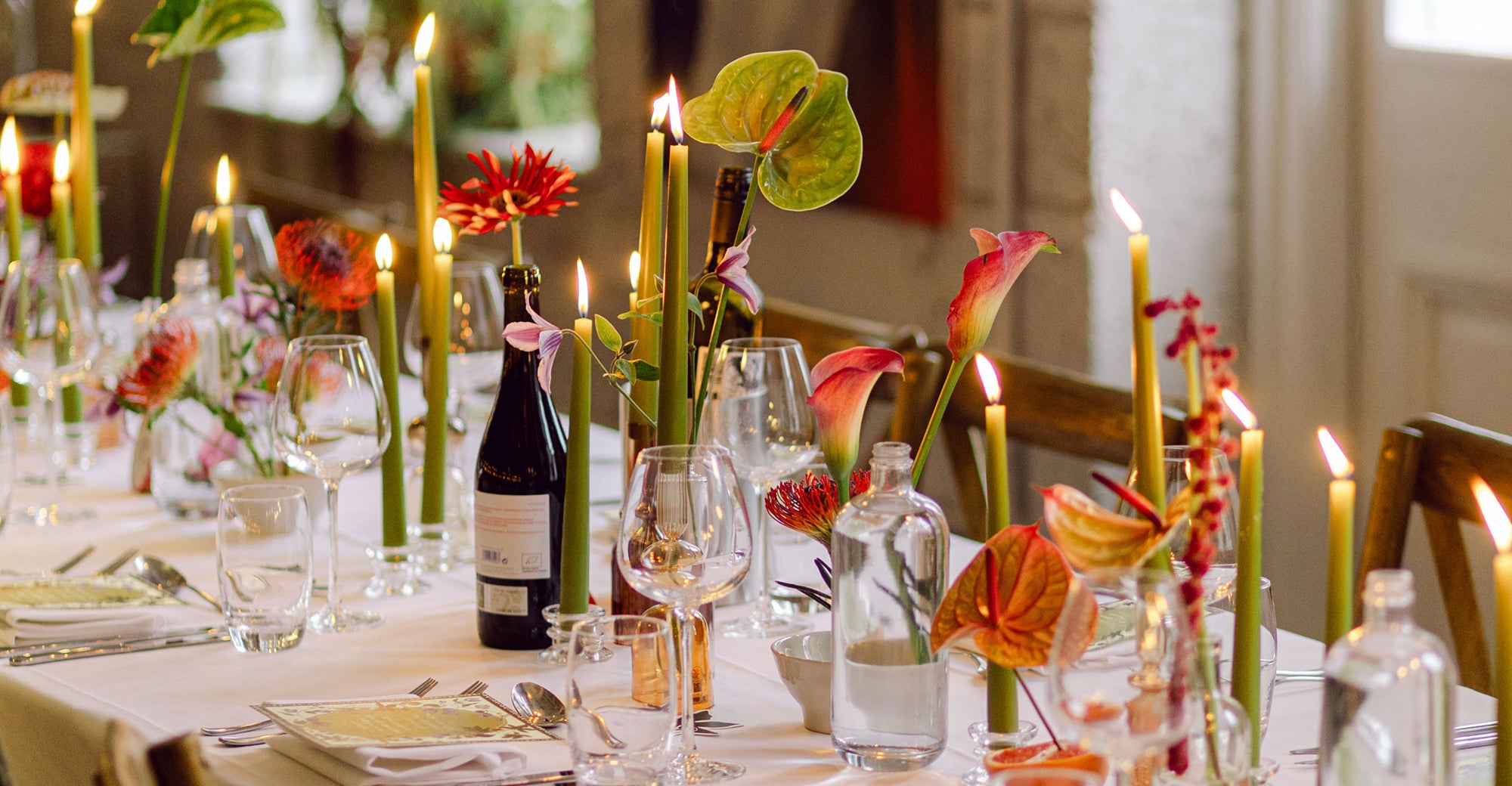 Decorative table setting with candles, flowers, and wine glasses in a formal dining room.