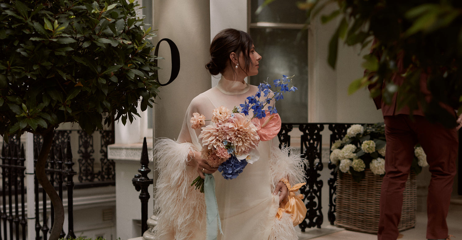 Woman in a white dress holding a bouquet of flowers in an outdoor setting.