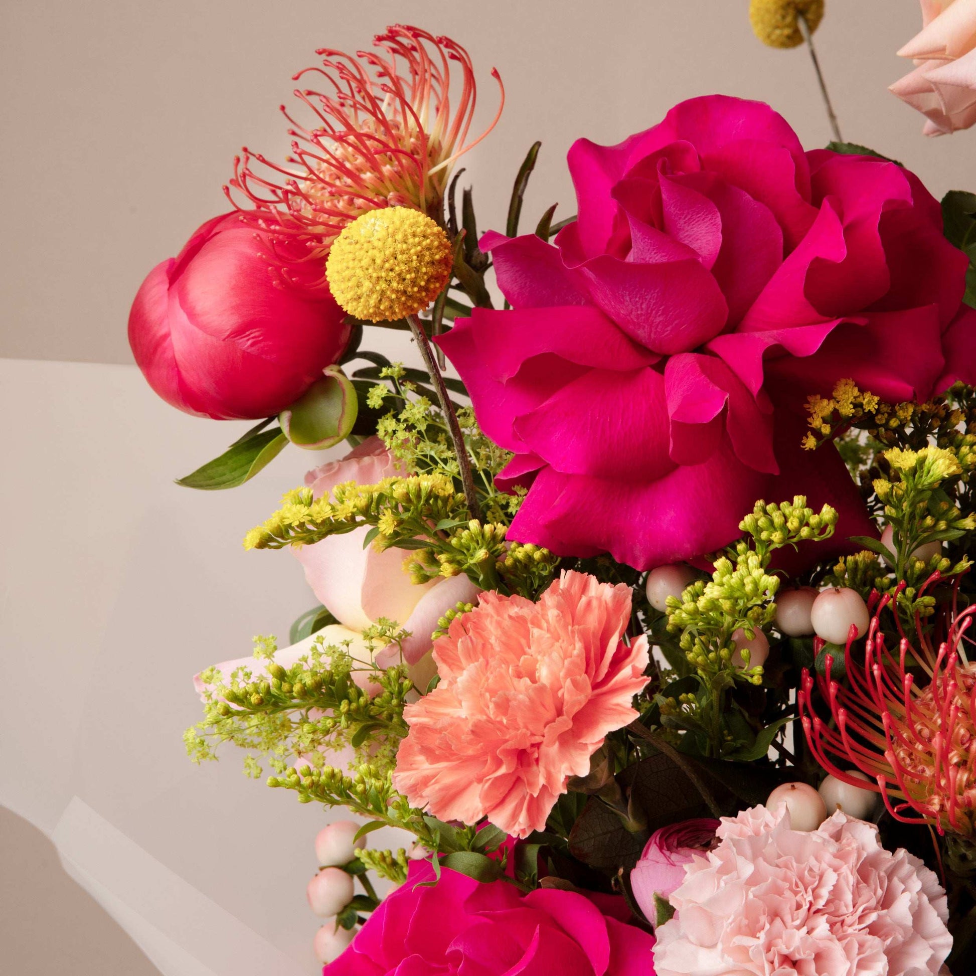 Colorful bouquet of flowers with pink, red, and yellow flowers on a neutral background