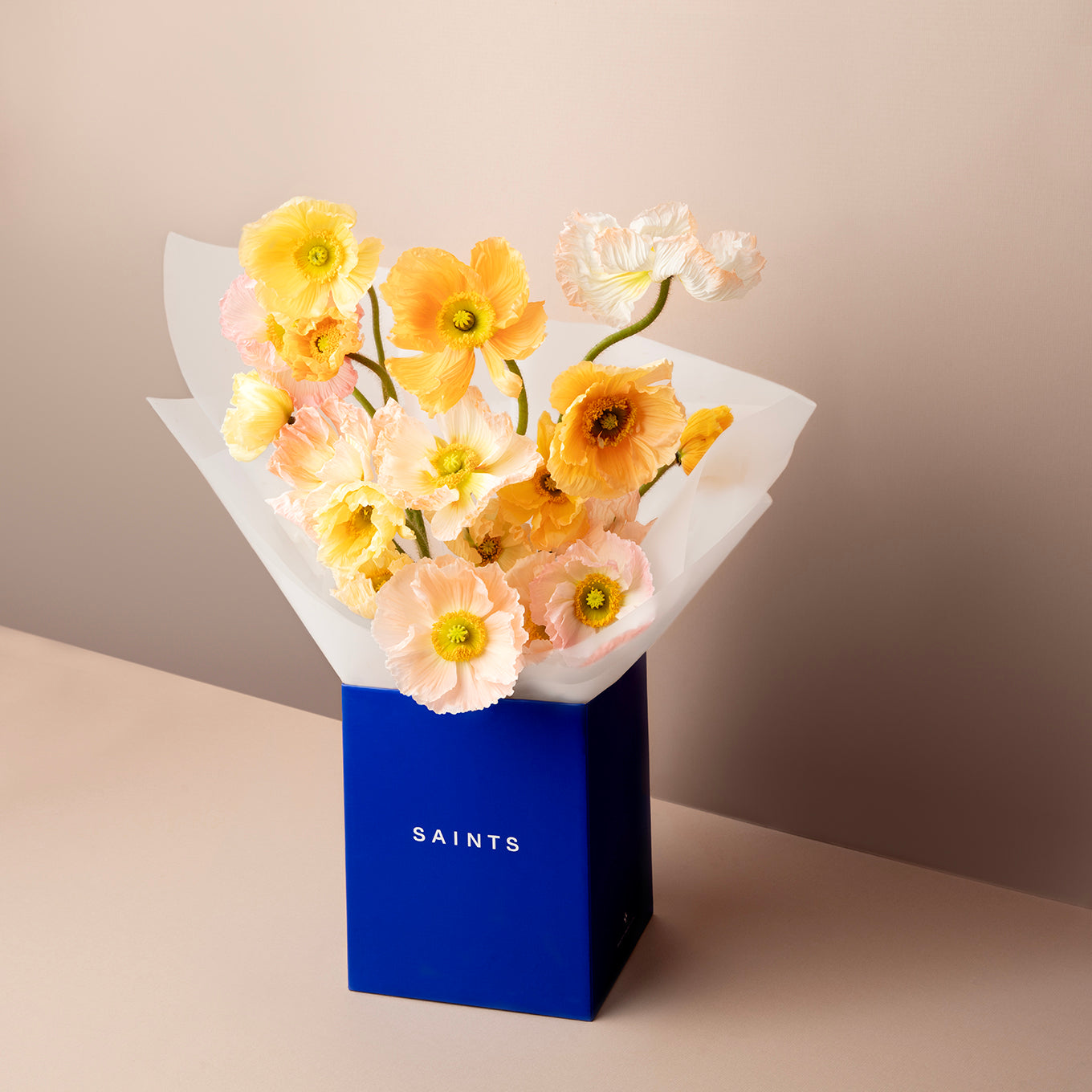 Bouquet of flowers in a blue box with 'SAINTS' branding on a beige background