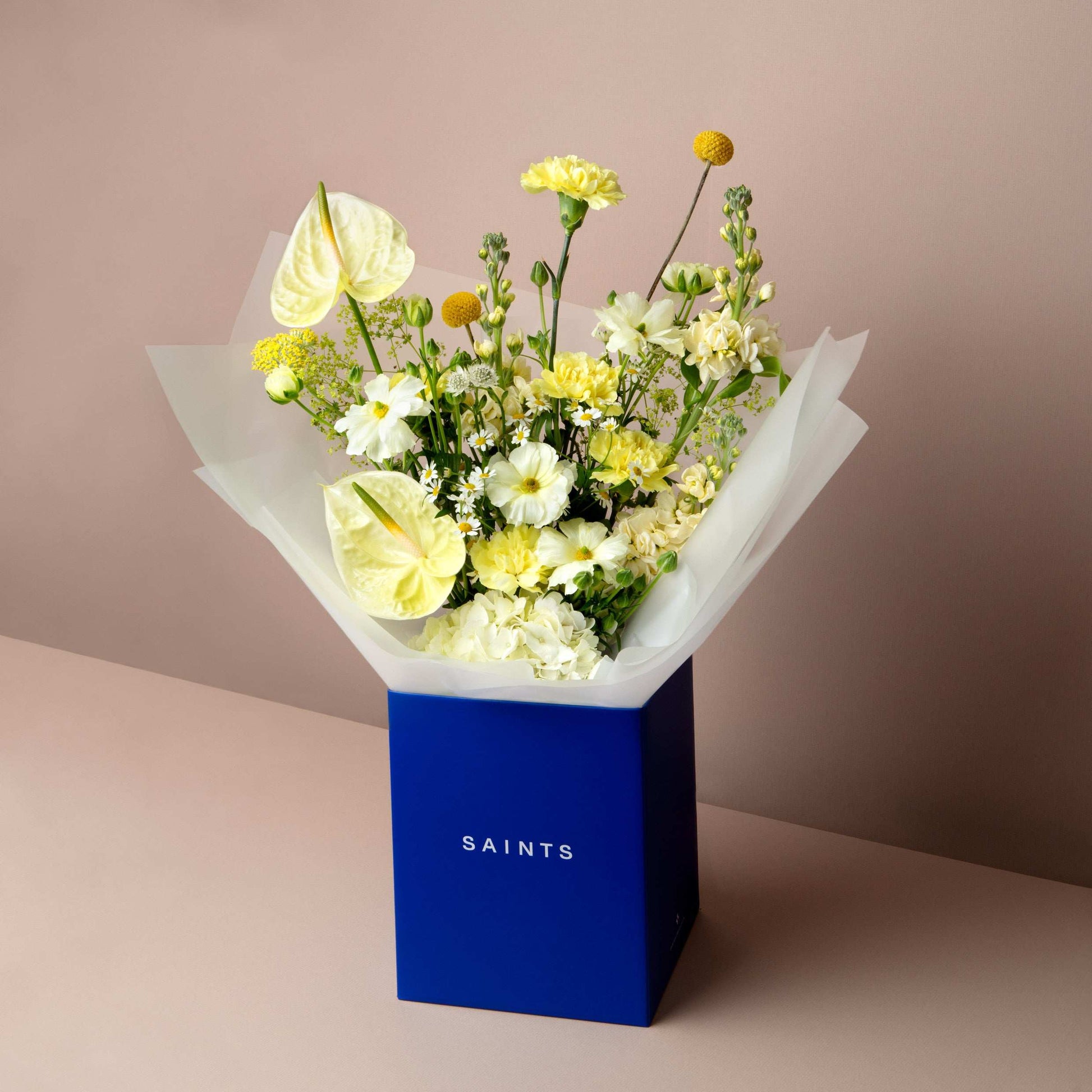 Bouquet of flowers in a blue box labeled 'SAINTS' on a beige background