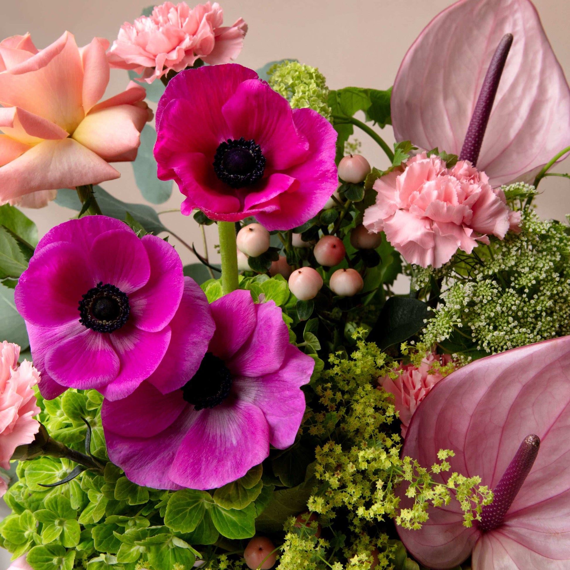 Bouquet of pink and purple flowers with greenery on a neutral background