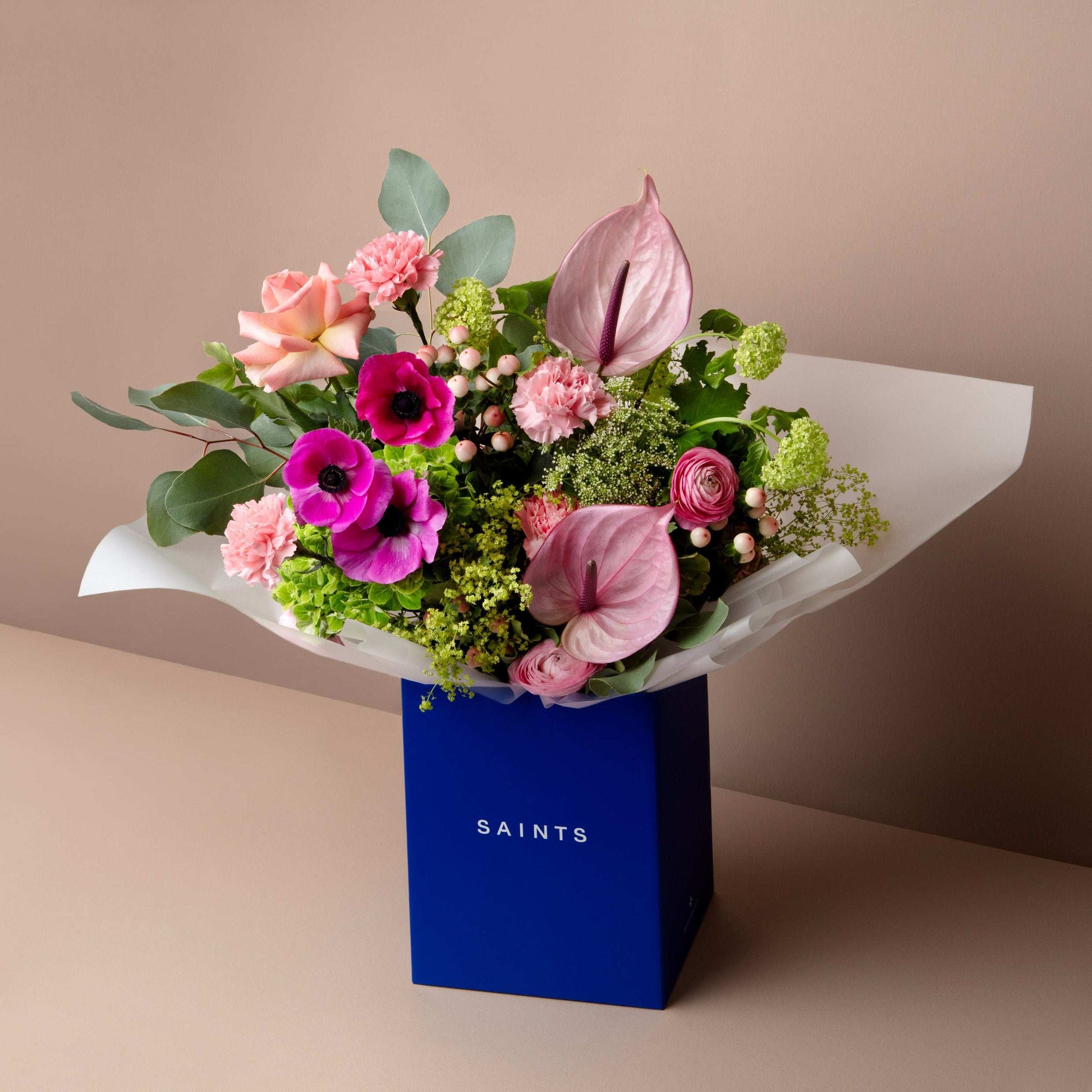 Bouquet of flowers in a blue box labeled 'SAINTS' on a beige background