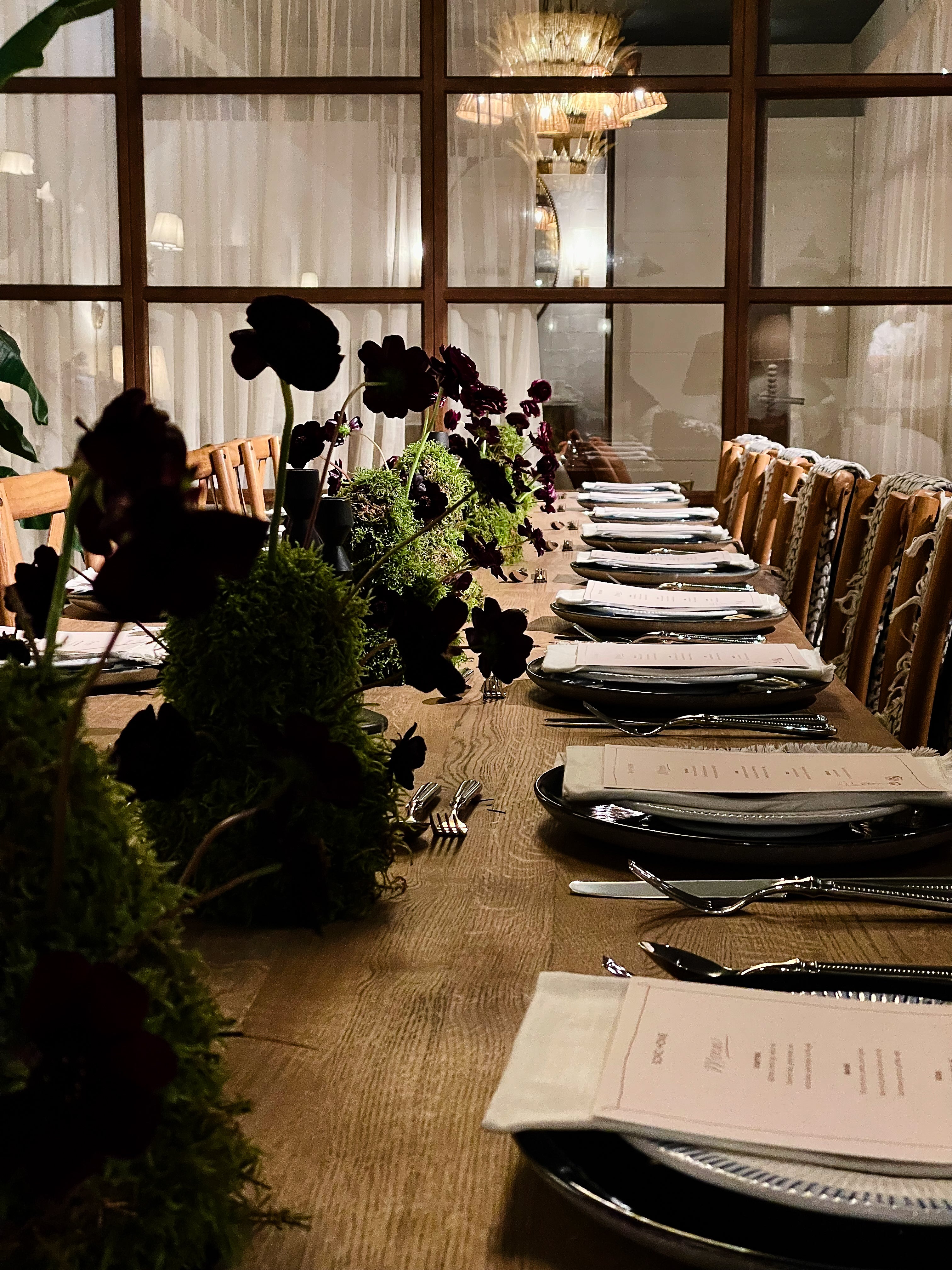Elegant dinner table setting with black floral arrangements and silverware.