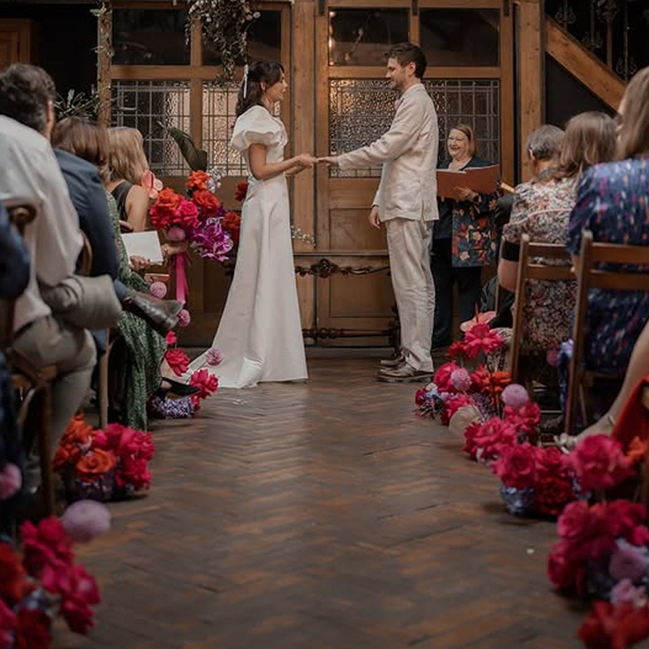 Wedding ceremony with a couple at the altar, surrounded by guests and floral decorations.