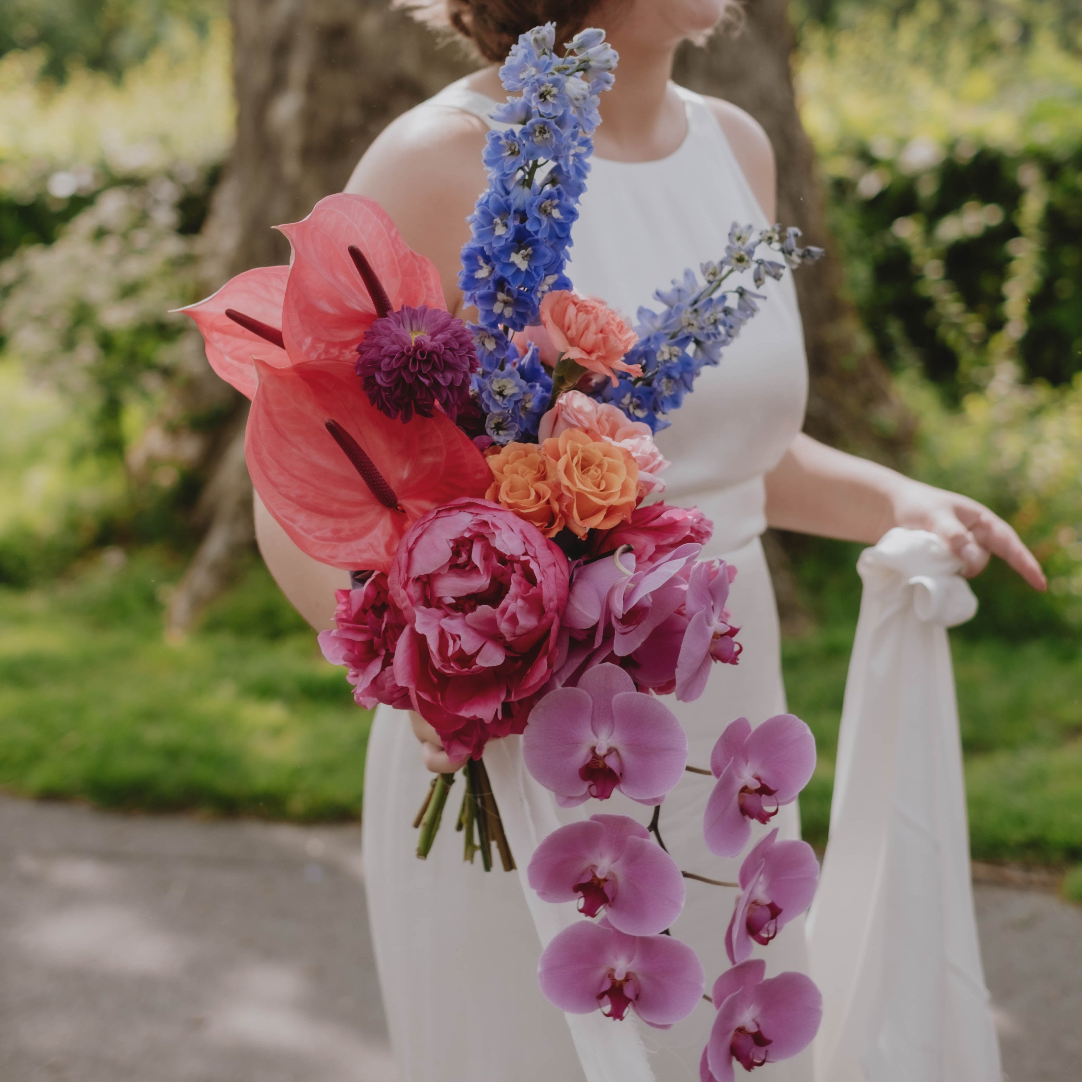 Person holding a colorful bouquet of flowers in an outdoor setting