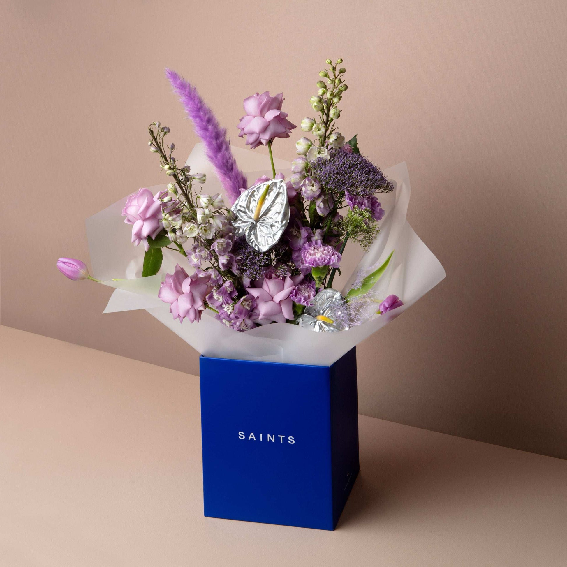 Bouquet of flowers in a blue box labeled 'SAINTS' on a beige background