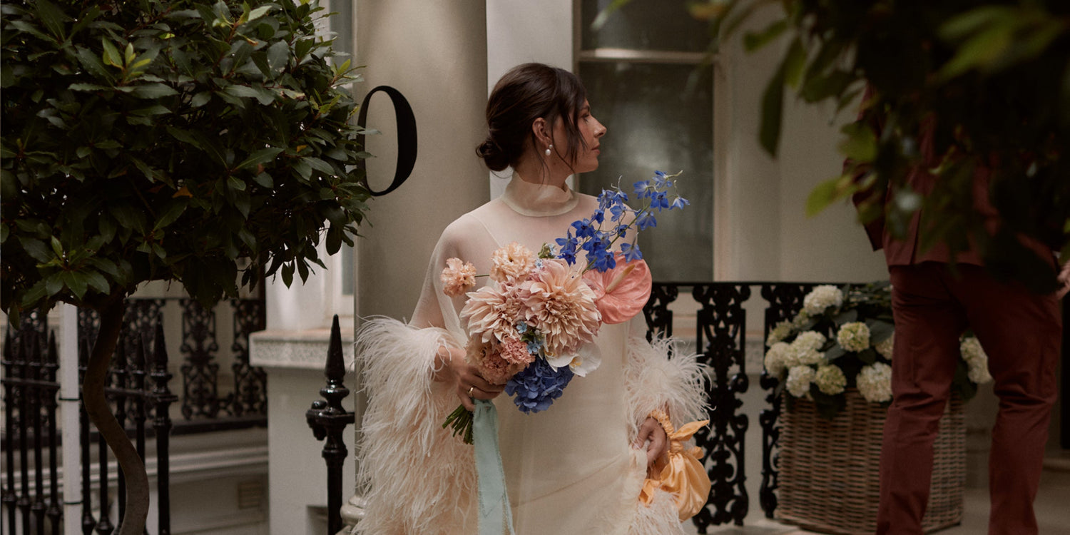 Woman in a white wedding dress holding flowers in an outdoor setting